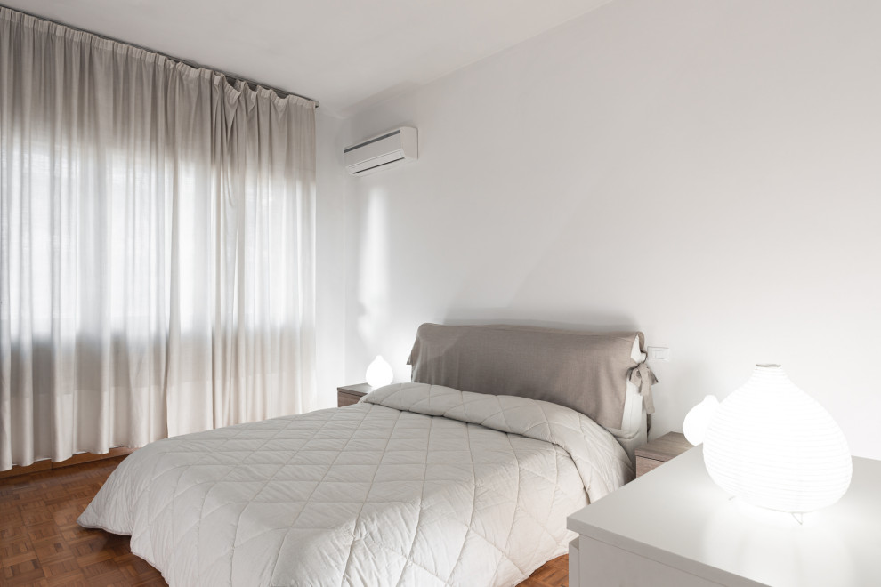 Cette image montre une petite chambre parentale design avec un mur blanc, parquet foncé et un sol marron.