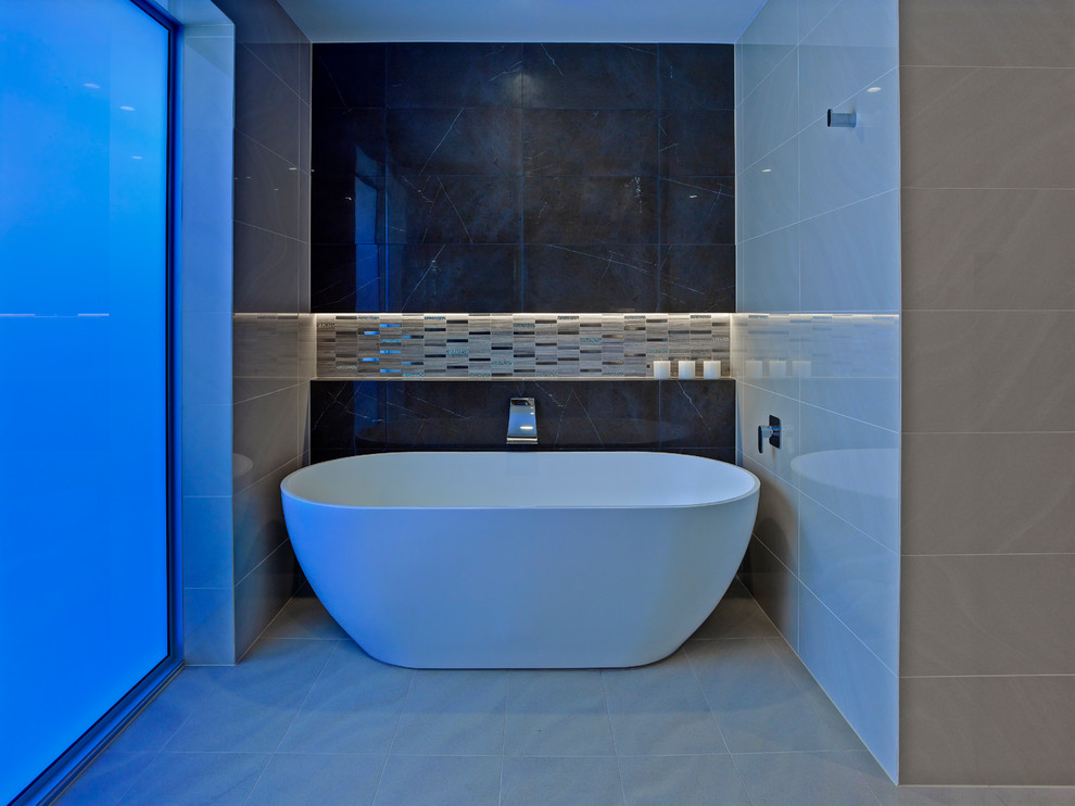 Photo of a large contemporary bathroom in Adelaide with flat-panel cabinets, dark wood cabinets, solid surface benchtops, a freestanding tub, beige tile, porcelain tile, beige walls and porcelain floors.