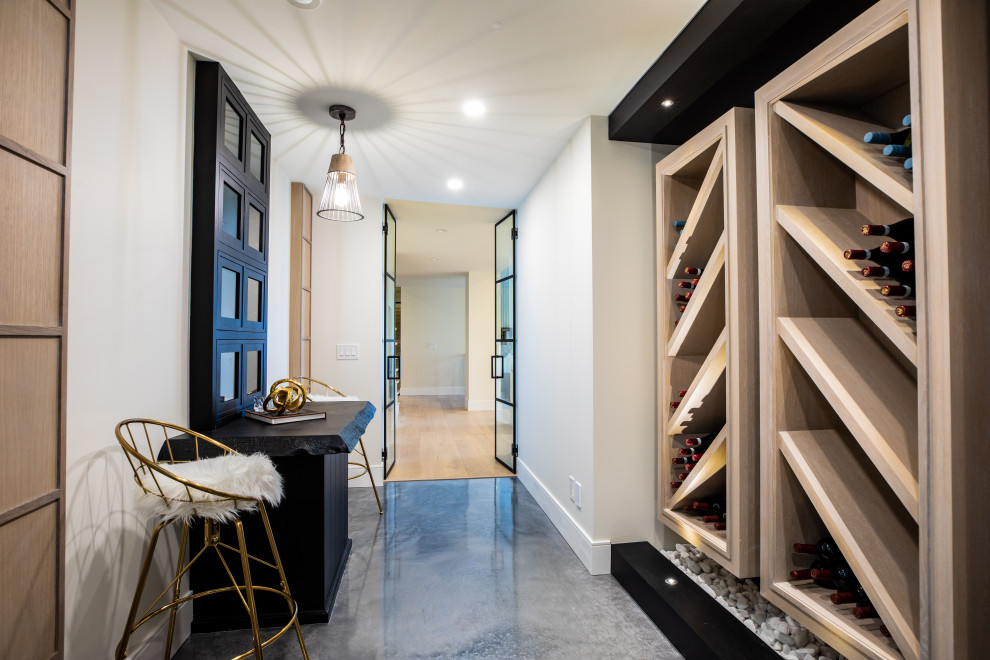 This is an example of a mid-sized country wine cellar in Calgary with concrete floors, display racks and grey floor.