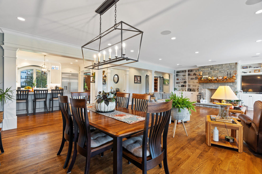 Inspiration for a large country dining room in Bridgeport with grey walls, medium hardwood floors, no fireplace, a stone fireplace surround and brown floor.