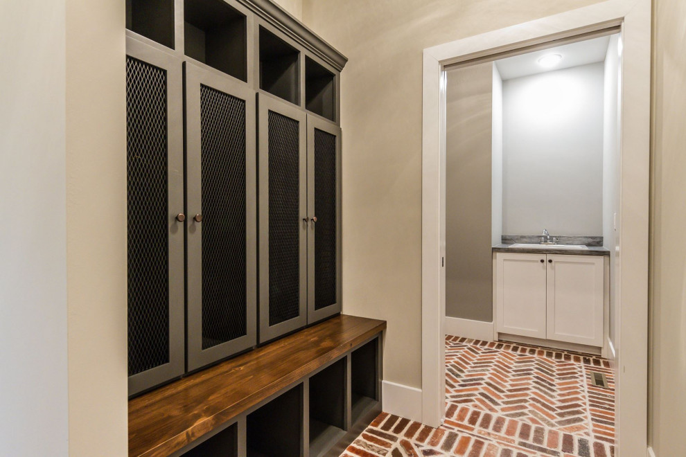 This is an example of a mid-sized transitional mudroom in St Louis with beige walls, brick floors and red floor.