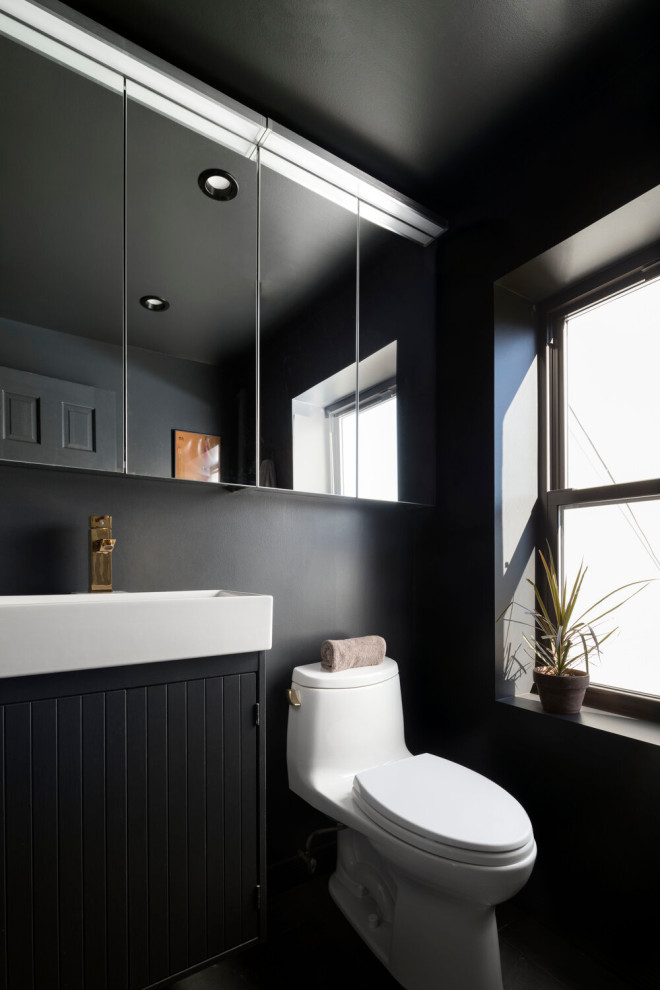 This is an example of a contemporary powder room in DC Metro with louvered cabinets, black cabinets, a two-piece toilet, black walls, a vessel sink, black floor and white benchtops.