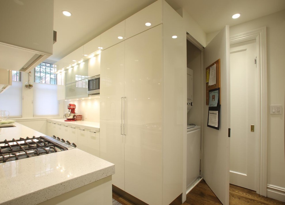 Mid-sized modern galley separate kitchen in New York with an undermount sink, flat-panel cabinets, white cabinets, stainless steel appliances, medium hardwood floors, no island, terrazzo benchtops, white splashback and stone tile splashback.