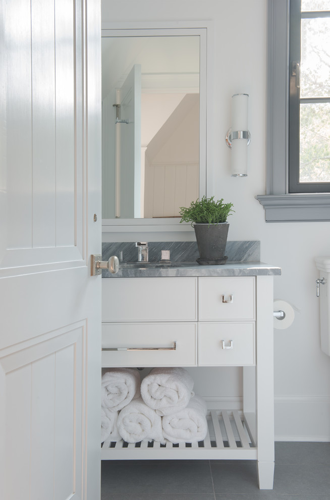 Inspiration for a mid-sized transitional powder room in New York with white cabinets, marble benchtops, gray tile, stone slab, porcelain floors, beaded inset cabinets, white walls, grey floor and grey benchtops.