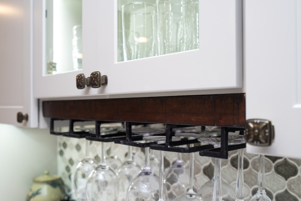 Example of a mid-sized transitional l-shaped laminate floor open concept kitchen design in DC Metro with a farmhouse sink, shaker cabinets, white cabinets, quartz countertops, gray backsplash, porcelain backsplash, stainless steel appliances and a peninsula