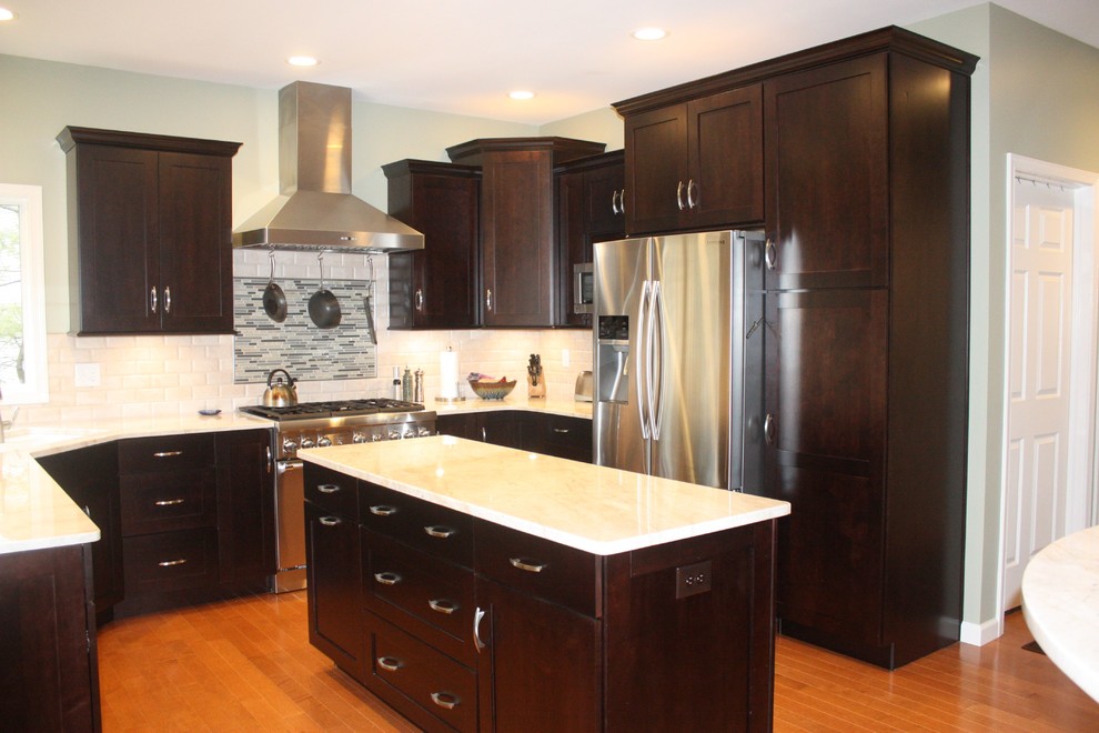 Example of a mid-sized trendy u-shaped medium tone wood floor eat-in kitchen design with shaker cabinets, dark wood cabinets, white backsplash, stainless steel appliances, an island, a double-bowl sink and subway tile backsplash