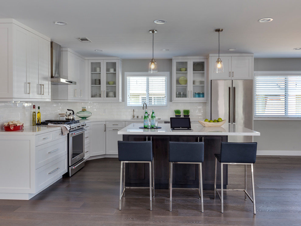 Photo of a mid-sized transitional l-shaped open plan kitchen in Los Angeles with an undermount sink, shaker cabinets, white cabinets, quartz benchtops, white splashback, subway tile splashback, stainless steel appliances, dark hardwood floors, with island and brown floor.