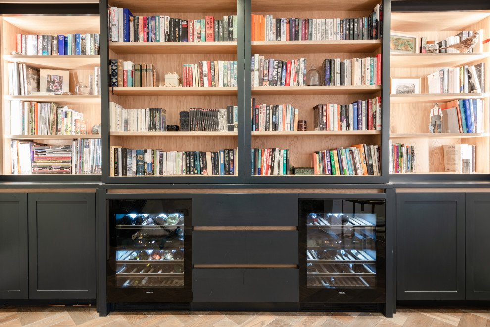 This is an example of a medium sized contemporary galley dry bar in London with shaker cabinets, black cabinets, medium hardwood flooring and feature lighting.