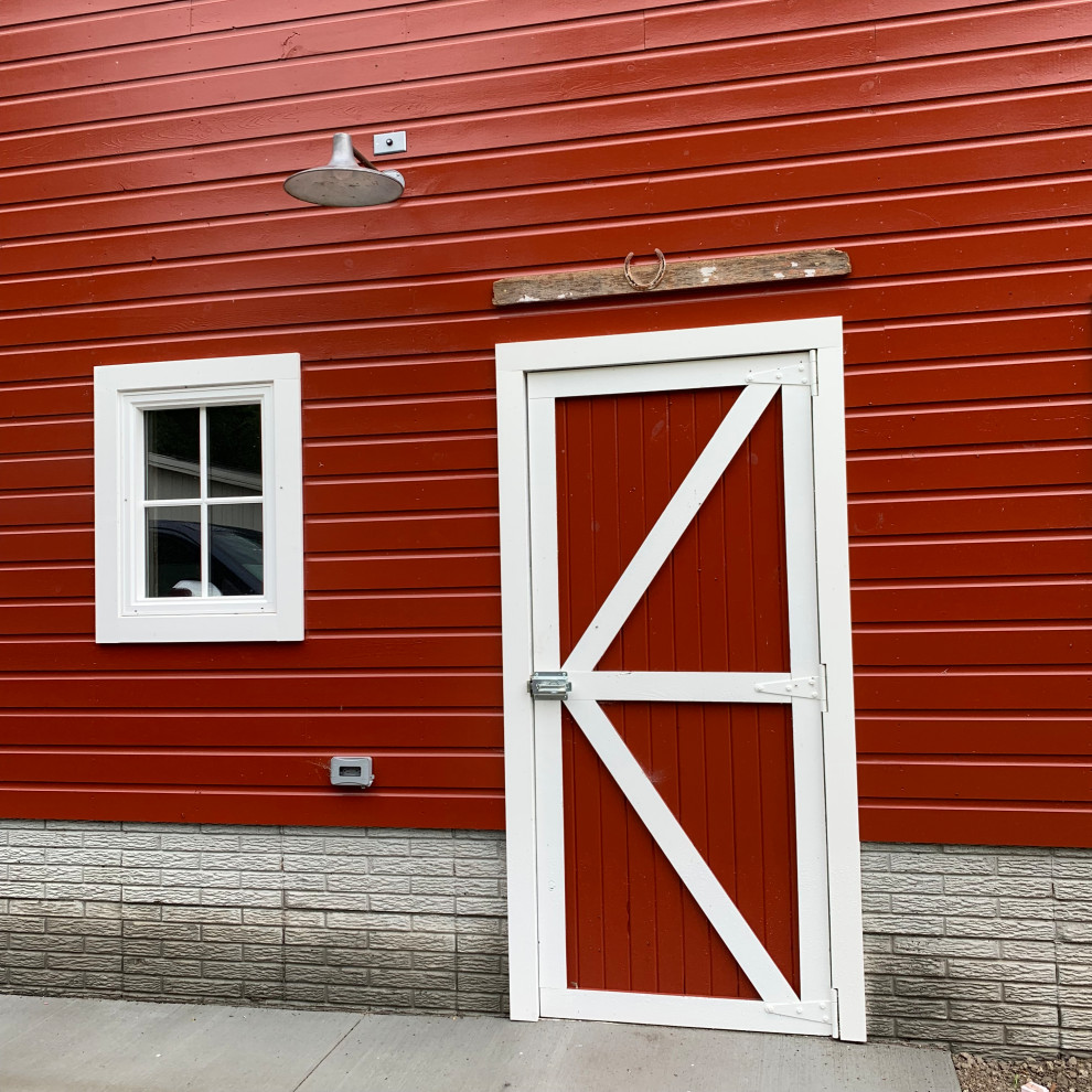 Aménagement d'une grande façade de maison rouge campagne en bois et bardage à clin à un étage avec un toit de Gambrel, un toit en shingle et un toit noir.