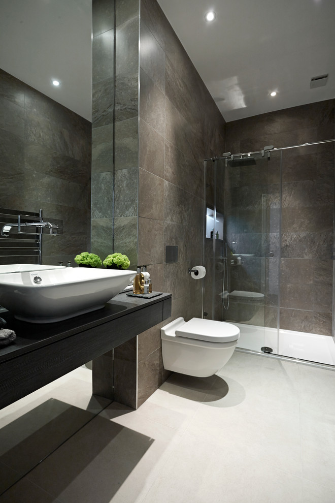 Contemporary bathroom in London with dark wood cabinets, a curbless shower, a wall-mount toilet, brown tile, porcelain tile, porcelain floors and a vessel sink.