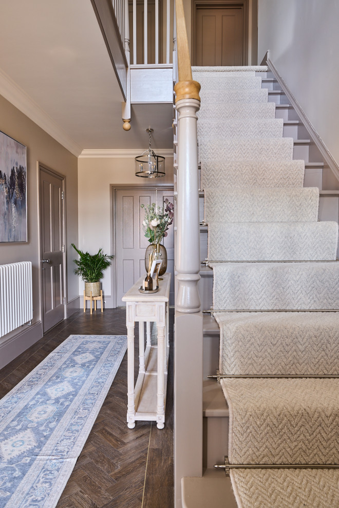 Large contemporary carpeted straight staircase in Essex with carpet risers and wood railing.