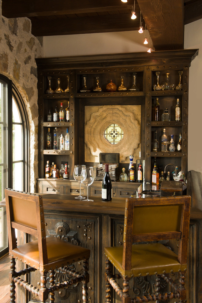 Mediterranean u-shaped seated home bar in San Diego with shaker cabinets, dark wood cabinets and dark hardwood floors.