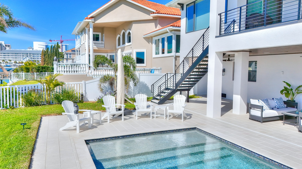 Ejemplo de casa de la piscina y piscina alargada moderna extra grande a medida en patio trasero con suelo de baldosas