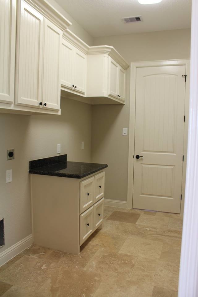 Inspiration for a mid-sized transitional single-wall utility room in Houston with a drop-in sink, recessed-panel cabinets, white cabinets, granite benchtops, beige walls and travertine floors.
