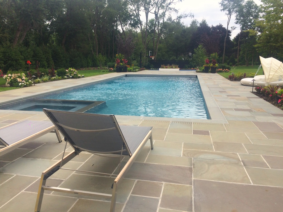 Design ideas for a large traditional backyard rectangular lap pool in New York with a hot tub and natural stone pavers.
