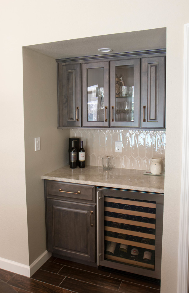 Small transitional home bar in Orlando with raised-panel cabinets, grey cabinets, quartzite benchtops, grey splashback, porcelain splashback, porcelain floors, brown floor and grey benchtop.