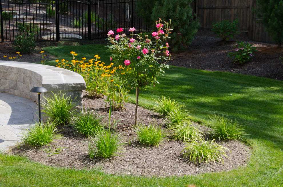 This is an example of a large country backyard garden in New York with a retaining wall and natural stone pavers.