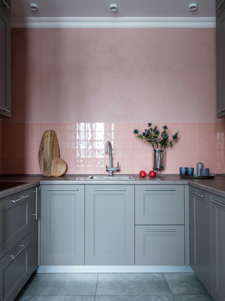 Small transitional u-shaped open plan kitchen in Moscow with a single-bowl sink, recessed-panel cabinets, grey cabinets, pink splashback, ceramic splashback, black appliances, no island and grey benchtop.