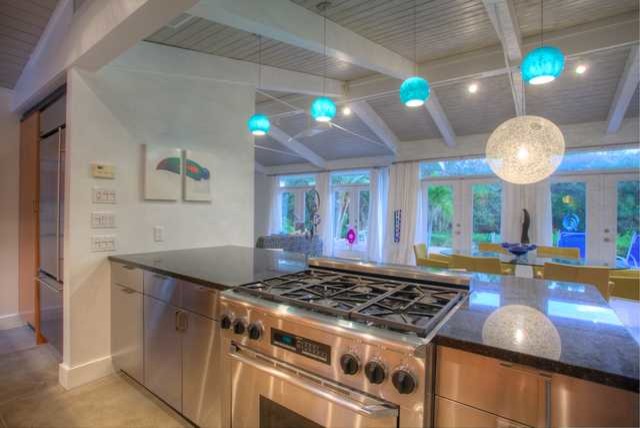 Design ideas for a mid-sized midcentury galley open plan kitchen in Tampa with an undermount sink, flat-panel cabinets, stainless steel cabinets, granite benchtops, metallic splashback, metal splashback and stainless steel appliances.