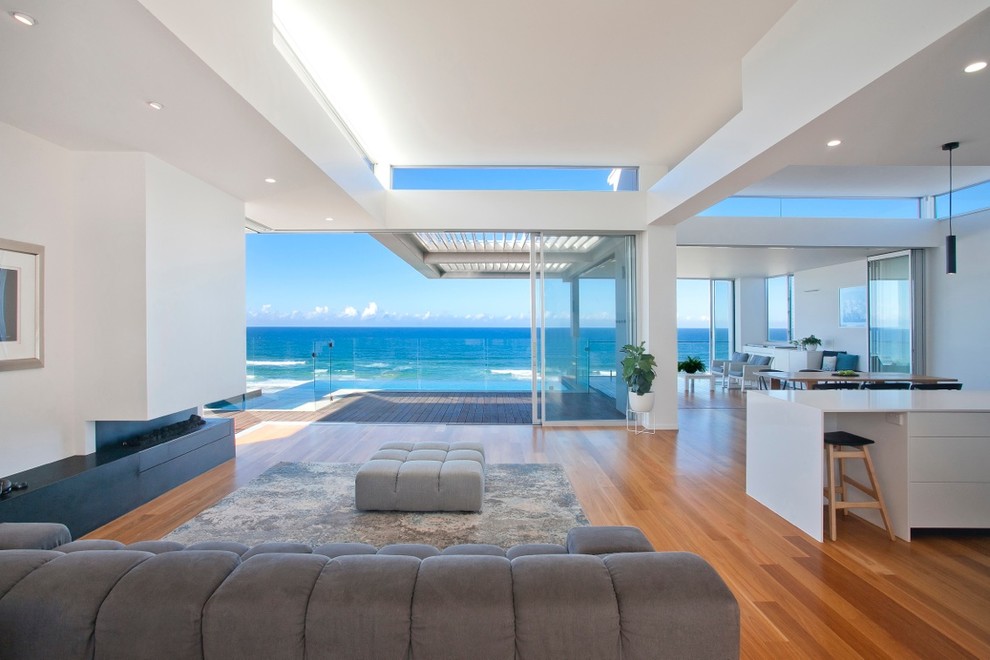 This is an example of a contemporary open concept living room in Sunshine Coast with white walls, medium hardwood floors, a ribbon fireplace and orange floor.