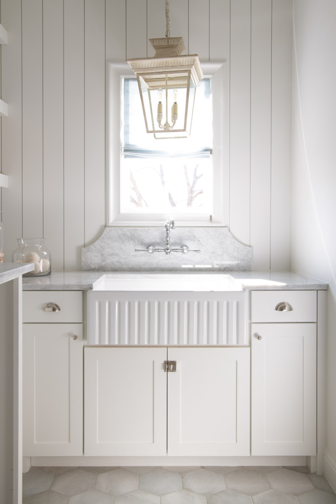 Idéer för stora vintage l-formade vitt tvättstugor enbart för tvätt, med en rustik diskho, skåp i shakerstil, vita skåp, marmorbänkskiva, vitt stänkskydd, vita väggar, klinkergolv i porslin, en tvättmaskin och torktumlare bredvid varandra och grått golv
