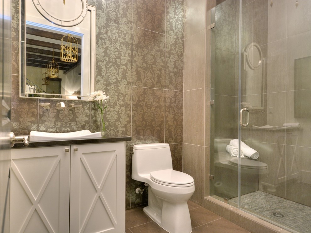 Photo of a transitional 3/4 bathroom in Austin with a vessel sink, recessed-panel cabinets, white cabinets, an alcove shower, a one-piece toilet, gray tile and grey walls.