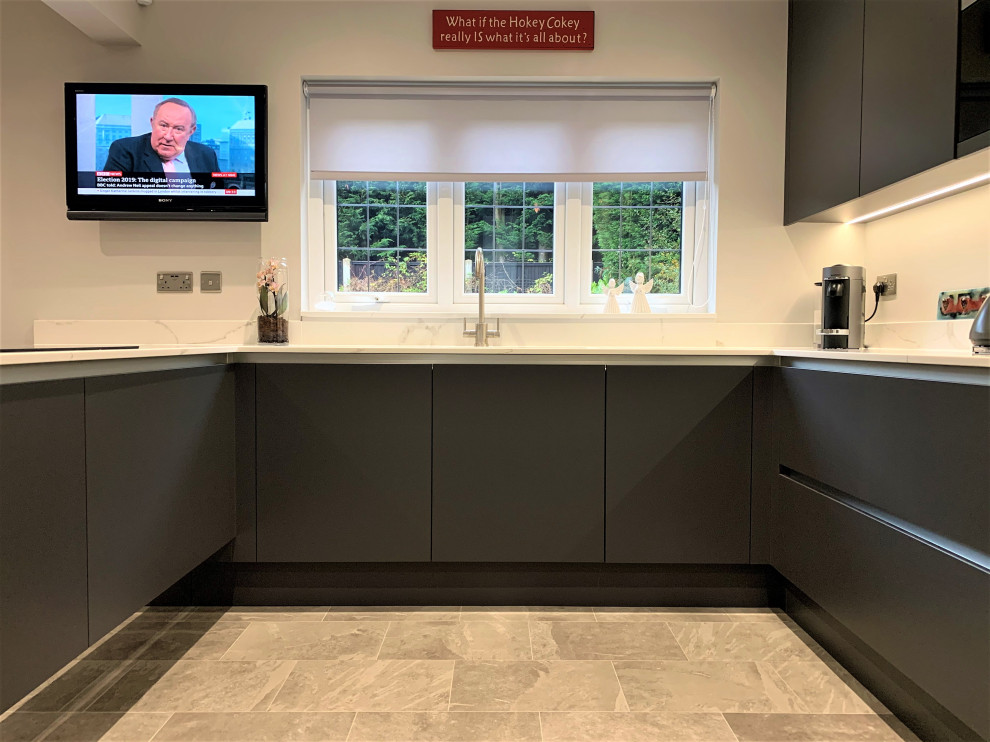 This is an example of a mid-sized contemporary u-shaped eat-in kitchen in Other with an undermount sink, flat-panel cabinets, grey cabinets, black appliances, vinyl floors, a peninsula and grey floor.
