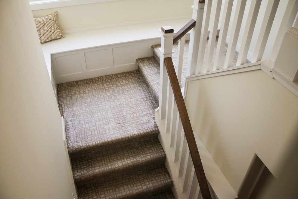 This is an example of a mid-sized contemporary carpeted u-shaped staircase in Other with carpet risers and wood railing.