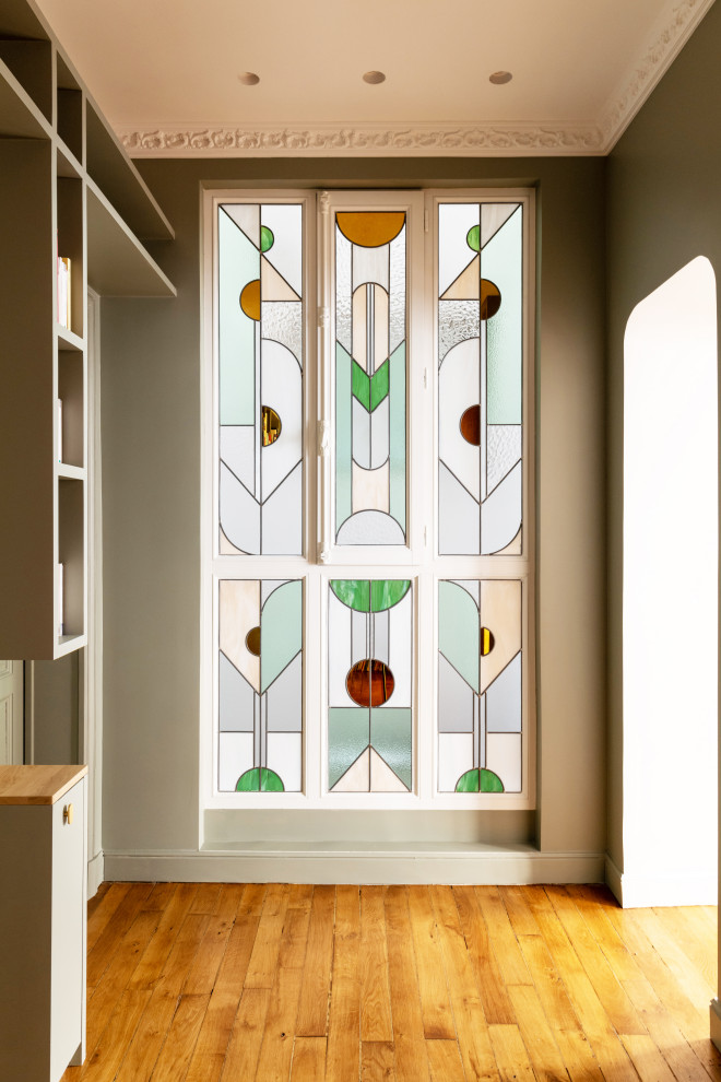 Diseño de distribuidor actual grande con paredes verdes, suelo de madera clara, puerta doble, puerta verde, suelo marrón y boiserie
