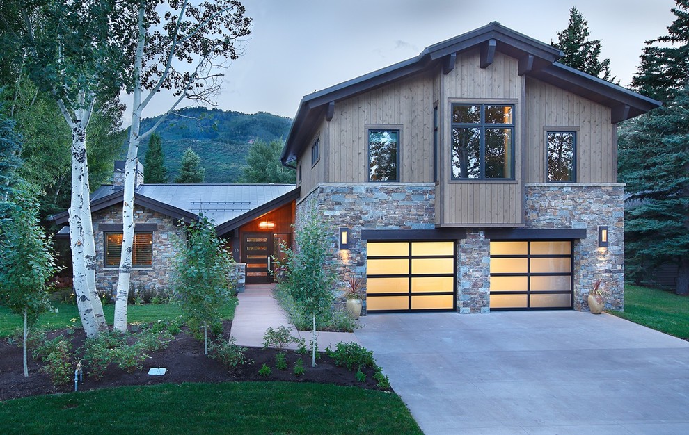 This is an example of a large contemporary two-storey brown house exterior in Salt Lake City with stone veneer, a gable roof and a metal roof.