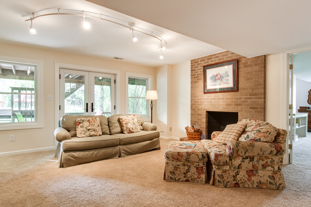 This is an example of a large traditional walk-out basement in Louisville with carpet, a standard fireplace, a brick fireplace surround and beige floor.
