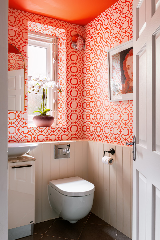 Powder room - small eclectic wallpaper powder room idea in London with orange walls