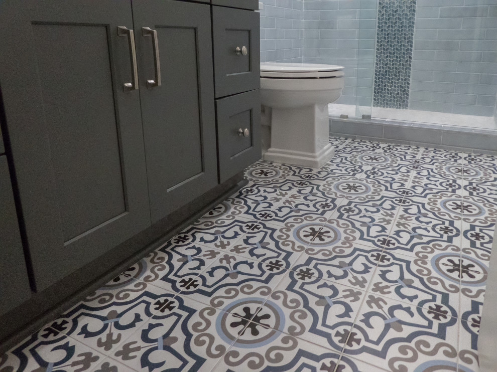 This is an example of a medium sized traditional family bathroom in Atlanta with shaker cabinets, grey cabinets, an alcove shower, a two-piece toilet, blue tiles, porcelain tiles, grey walls, porcelain flooring, a submerged sink, engineered stone worktops, multi-coloured floors, a sliding door and white worktops.