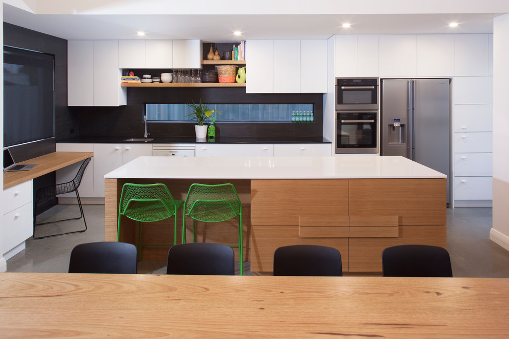 Inspiration for a contemporary kitchen in Perth with flat-panel cabinets, white cabinets, black splashback, stainless steel appliances and concrete floors.