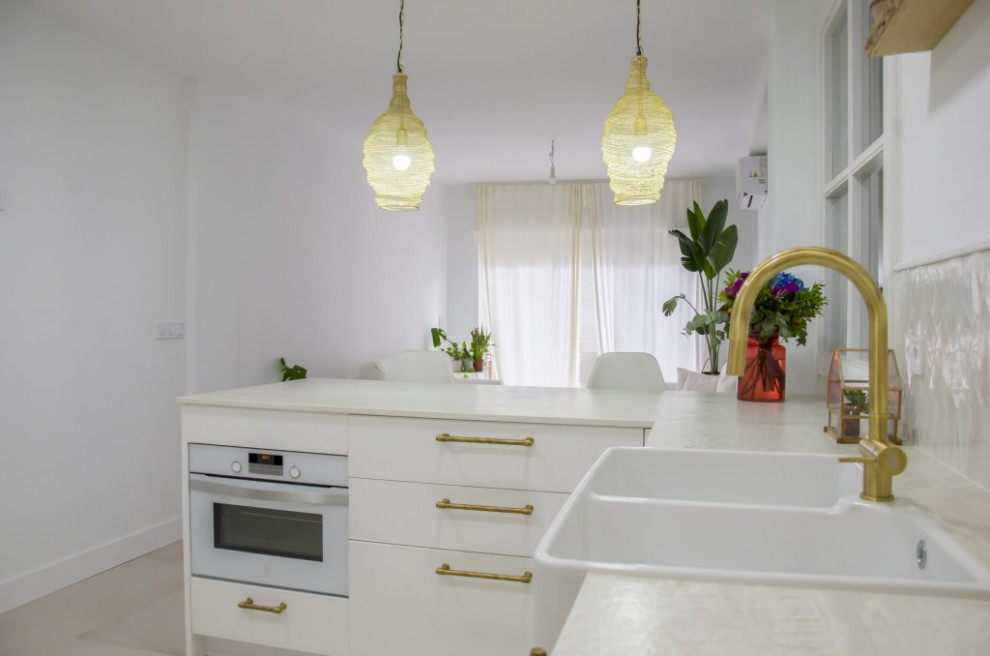 Imagen de cocinas en U ecléctico de tamaño medio abierto con fregadero sobremueble, puertas de armario blancas, electrodomésticos blancos, península y suelo blanco
