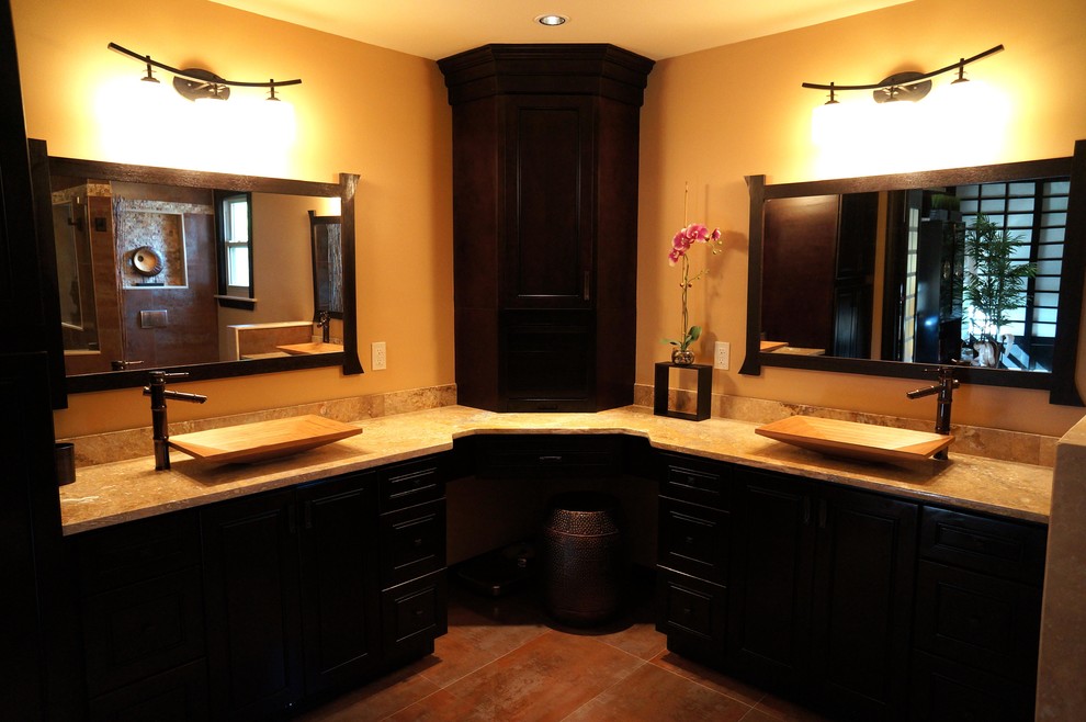 This is an example of a mid-sized asian master bathroom in Philadelphia with slate floors, an alcove shower, brown walls, a vessel sink, raised-panel cabinets, black cabinets, a wall-mount toilet and limestone benchtops.