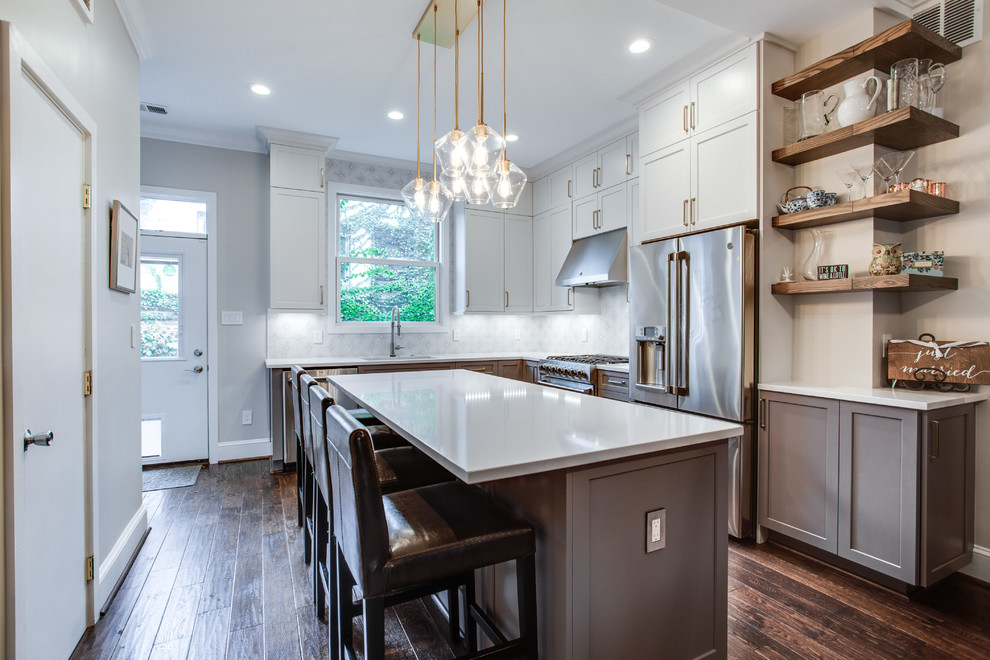 Inspiration for a large transitional l-shaped medium tone wood floor and brown floor eat-in kitchen remodel in DC Metro with an island, white countertops, an undermount sink, shaker cabinets, white cabinets, solid surface countertops, white backsplash, ceramic backsplash and stainless steel appliances