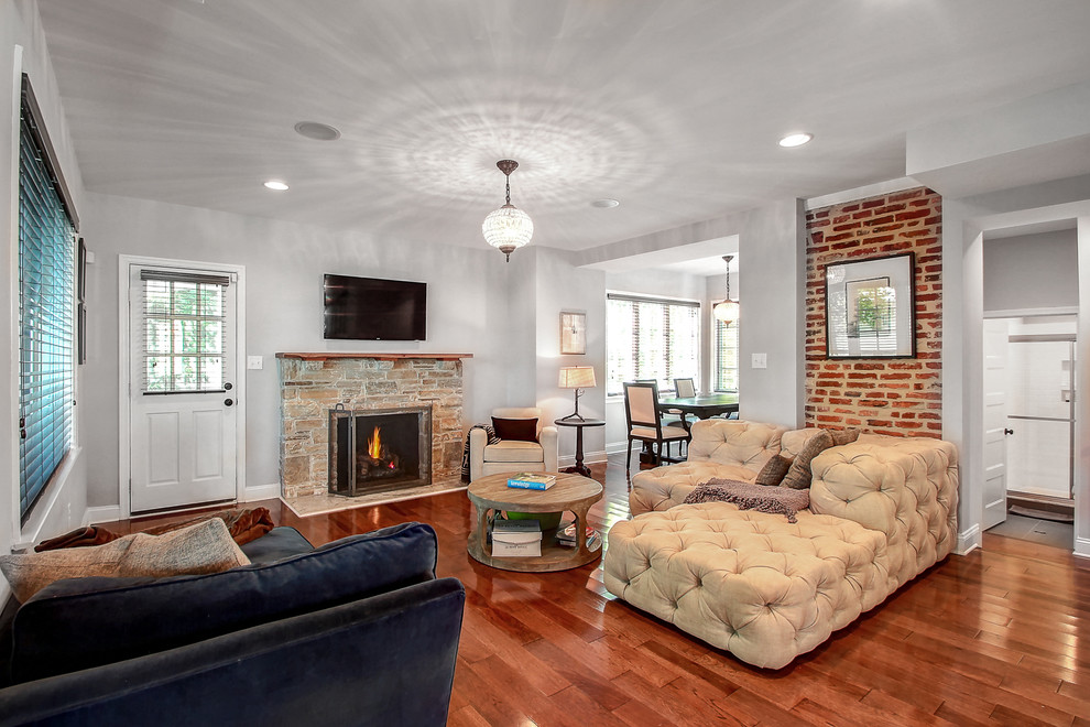 Inspiration for a mid-sized traditional open concept family room in Baltimore with grey walls, medium hardwood floors, a standard fireplace, a stone fireplace surround and a wall-mounted tv.