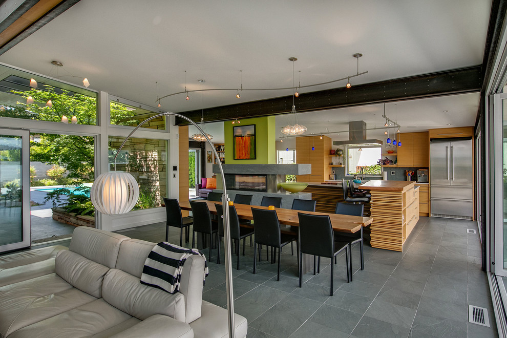 Photo of a mid-sized contemporary dining room in Seattle with white walls, slate floors and a two-sided fireplace.