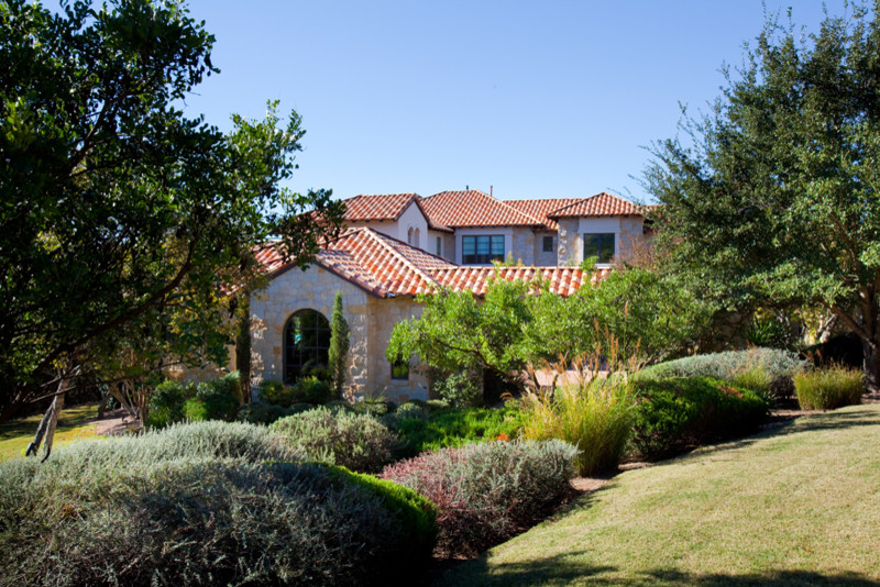 This is an example of a large mediterranean two-storey beige exterior in Austin with stone veneer.
