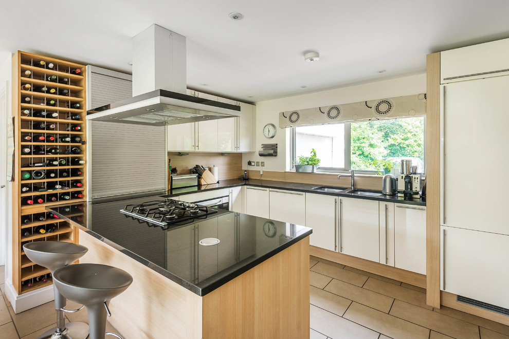 Contemporary u-shaped kitchen in Kent with a double-bowl sink, flat-panel cabinets, beige cabinets, beige splashback, panelled appliances and a peninsula.