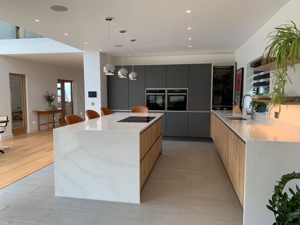 This is an example of a mid-sized contemporary l-shaped kitchen in Kent with an undermount sink, flat-panel cabinets, white cabinets, panelled appliances, porcelain floors, with island, beige floor and white benchtop.