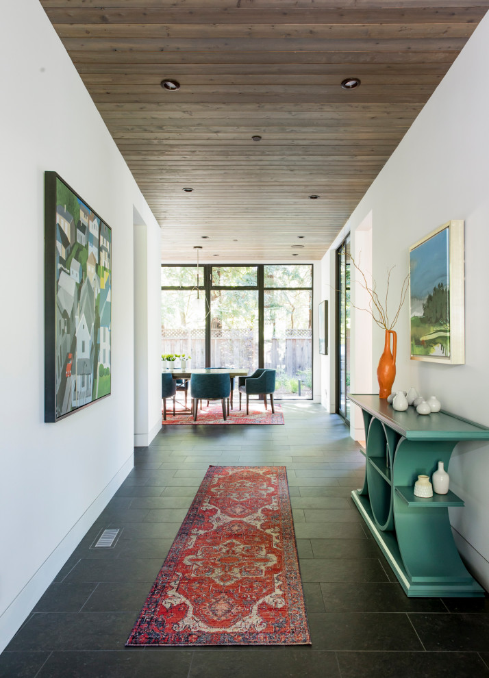 This is an example of a large contemporary hallway in San Francisco with white walls, porcelain floors, black floor and wood.