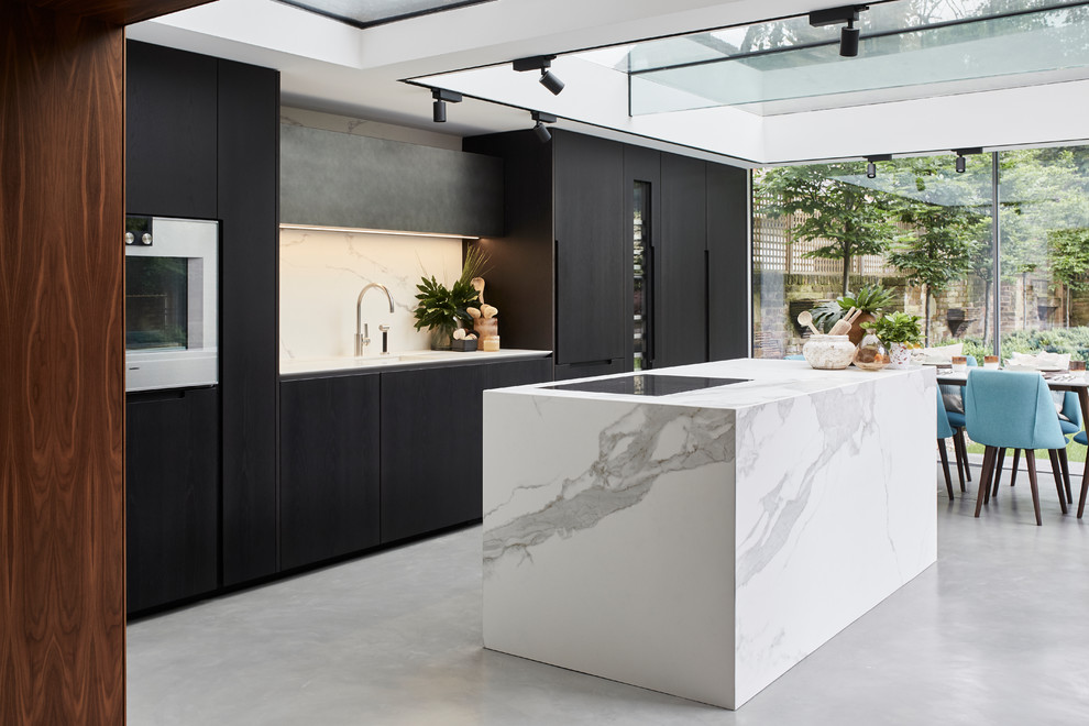 Photo of a mid-sized contemporary single-wall eat-in kitchen in London with an undermount sink, flat-panel cabinets, dark wood cabinets, marble benchtops, white splashback, marble splashback, panelled appliances, concrete floors, with island, grey floor and white benchtop.