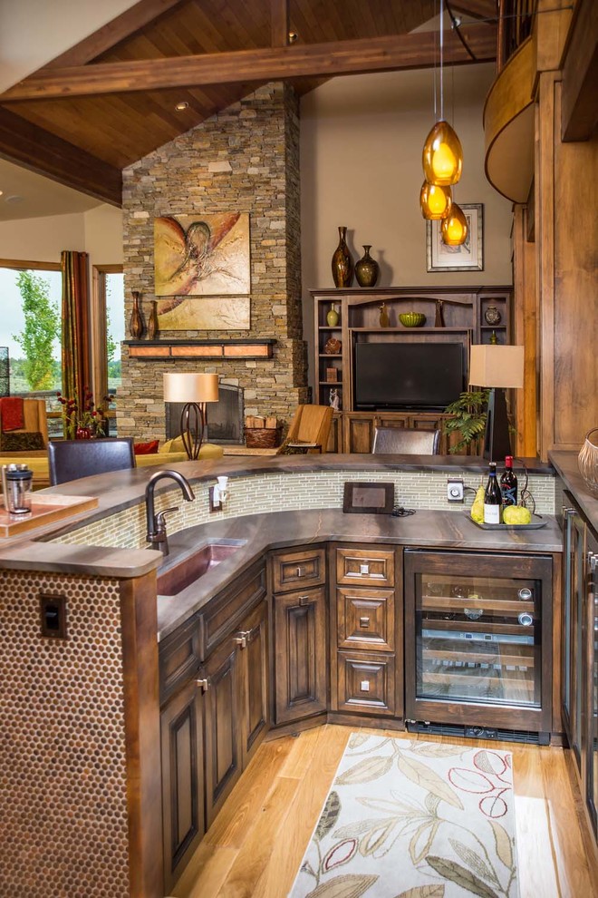 Design ideas for a large country l-shaped seated home bar in Other with an undermount sink, shaker cabinets, dark wood cabinets, granite benchtops, glass tile splashback and light hardwood floors.