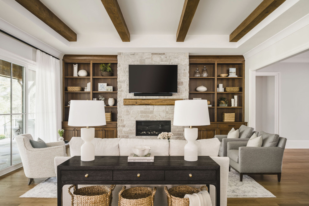 Diseño de sala de estar abierta tradicional renovada de tamaño medio con paredes beige, suelo de madera en tonos medios, todas las chimeneas, marco de chimenea de piedra, televisor colgado en la pared y vigas vistas