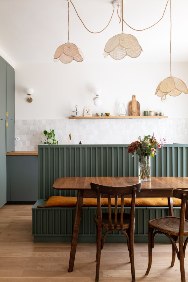 パリにある高級な中くらいな北欧スタイルのおしゃれなキッチン (ドロップインシンク、インセット扉のキャビネット、緑のキャビネット、木材カウンター、ベージュキッチンパネル、ライムストーンのキッチンパネル、パネルと同色の調理設備、淡色無垢フローリング、茶色い床、茶色いキッチンカウンター) の写真