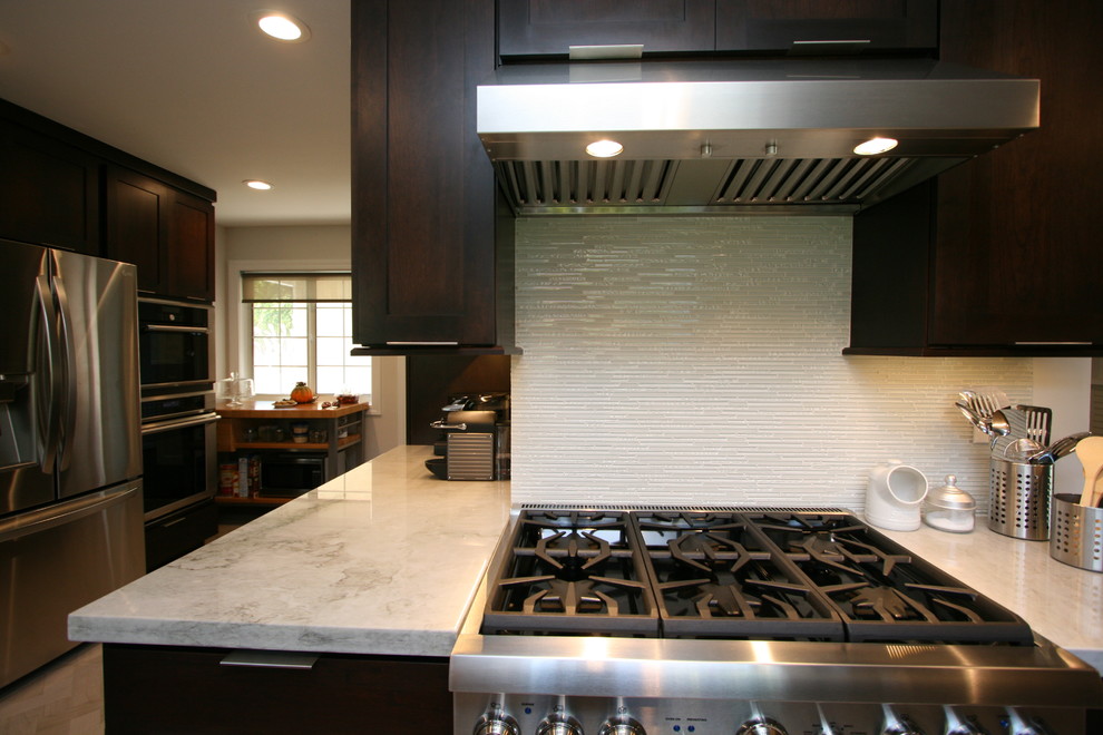 Kitchen - mid-sized transitional l-shaped porcelain tile kitchen idea in Orange County with a double-bowl sink, recessed-panel cabinets, dark wood cabinets, quartzite countertops, white backsplash, glass tile backsplash, stainless steel appliances and no island
