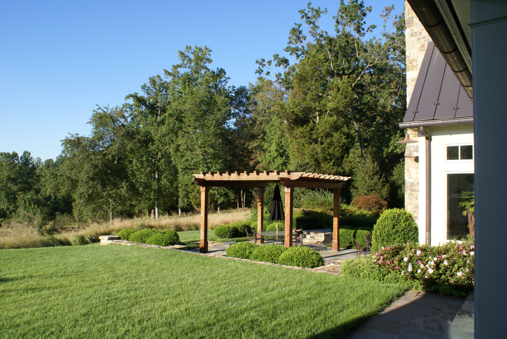 Design ideas for a large country backyard patio in DC Metro with natural stone pavers and a pergola.