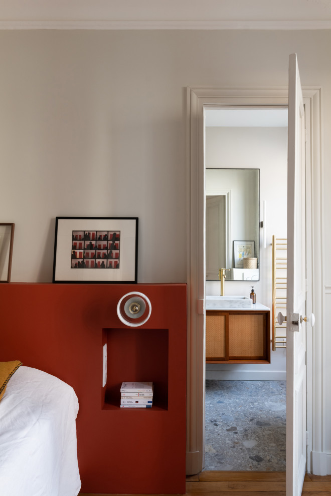 パリにある広いミッドセンチュリースタイルのおしゃれな主寝室 (ベージュの壁、無垢フローリング、標準型暖炉、石材の暖炉まわり)